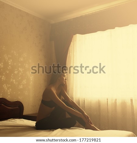 Pretty Sweet, Lonely Girl Sitting On The Bed Next To The Window At Dawn