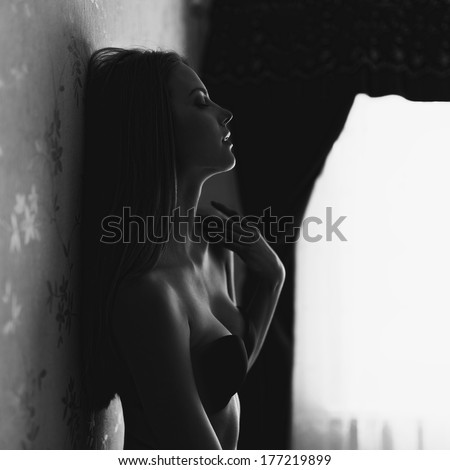 Black and white fashion portrait of a beautiful girl in lingerie near wall