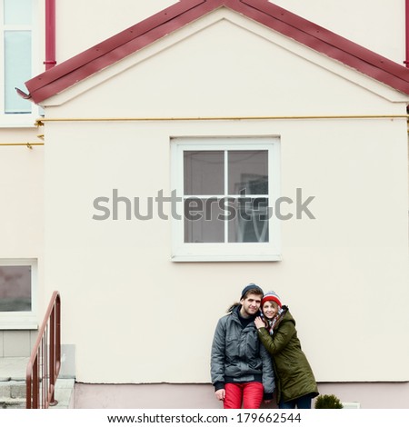 Cute love couple smiling and standing near the house with a window