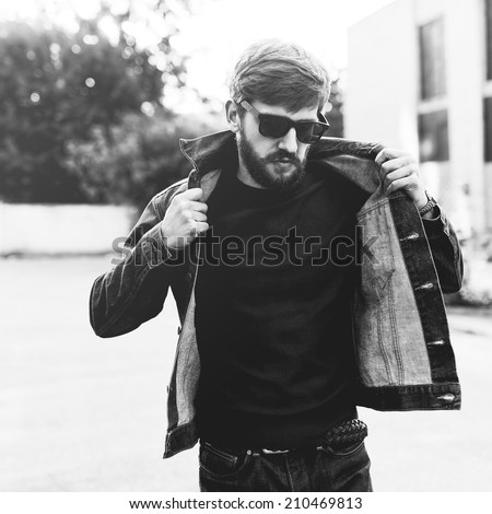 Brutal black and white portrait of a fashionable man with a beard and glasses