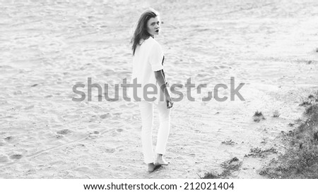 Beautiful single woman goes barefoot on the beach one , black and white