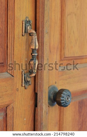 golden door handle with old design on brown wood door