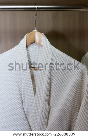 white bathrobes hanging in wooden closet