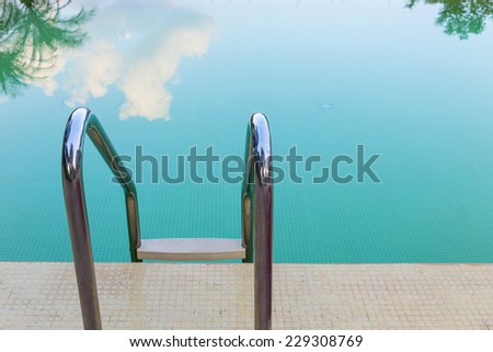 steel stair of green swimming pool with sky reflection