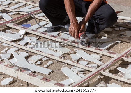 man worker repairing steel fence with electric saw tool