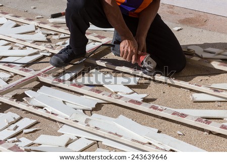man worker repairing steel fence with electric saw tool