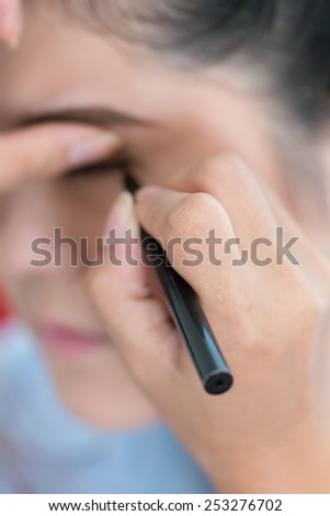 makeup beauty with brush eye liner on pretty woman face