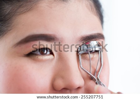 makeup artist using eyelash curler on woman face