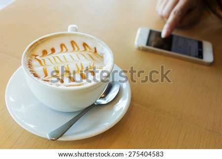 hot of coffee drink on wooden table bar with mobile phone in the cafe