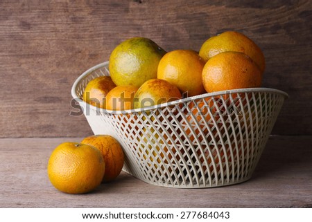 orange fruit in white basket on wood table background