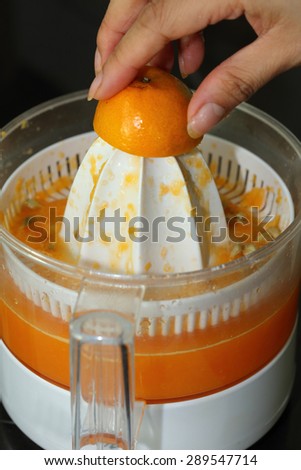 orange fruit squeezed with woman hand in juicer machine, orange juice