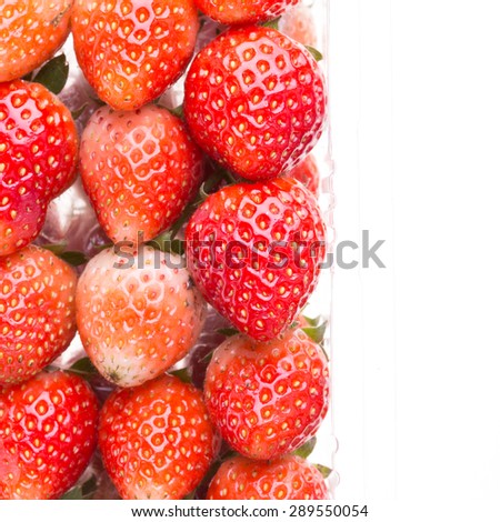 red ripe strawberry in plastic box of packaging for sale, isolated on white background