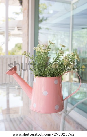 flowers vase decorated on mirror table at living room, artificial flowers in vase watering can