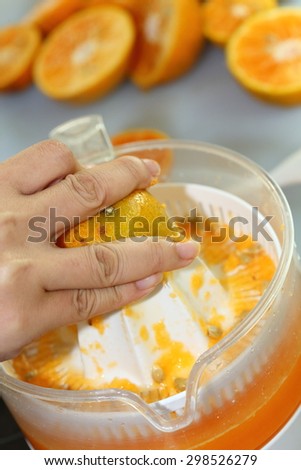 orange fruit squeezed with woman hand in juicer machine, orange juice