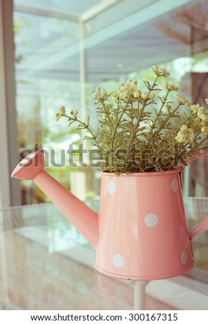 flowers vase decorated on mirror table at living room, artificial flowers in vase watering can