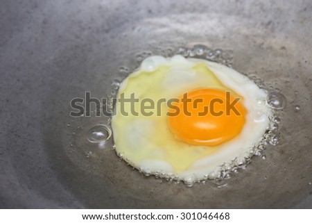 cooking fried egg in hot pan with oil