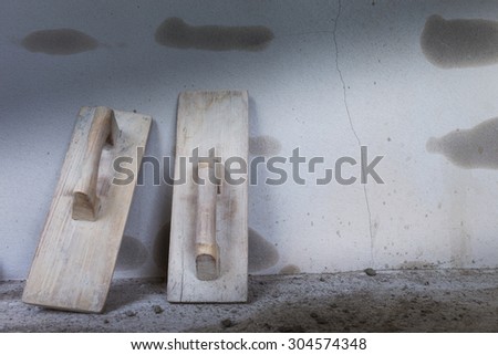 wood trowel and cement wall in construction site, trowel handheld tool used spread mortar or plaster
