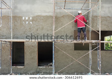 plasterer cement concrete man worker stand on scaffold steel plastering wall of residential construction house