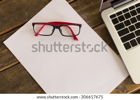 white paper blank on wood table office with eyeglasses and laptop notebook computer
