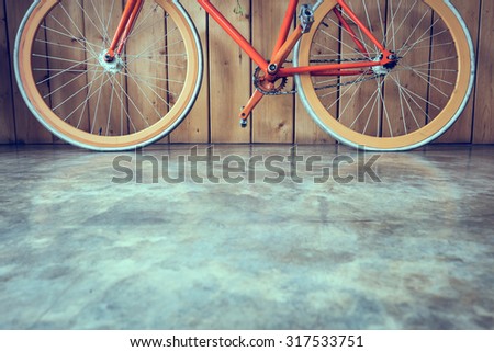 fixed gear bicycle parked with wood wall and cement floor, close up image part of bicycle