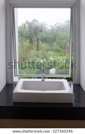 washbasin in bathroom with transparent mirror window nature view