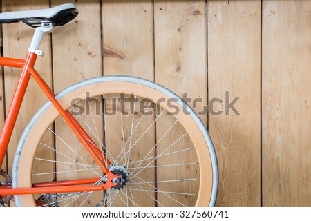 orange bicycle parked with wood wall, close up image part of bicycle