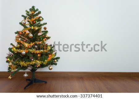 christmas tree decoration in empty room with white wall and wooden laminate floor
