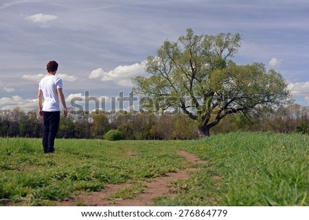 A man stands in front of a big tree