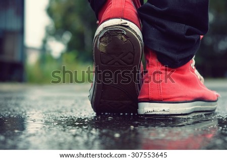 Guy goes in red sneakers on the street in the rain