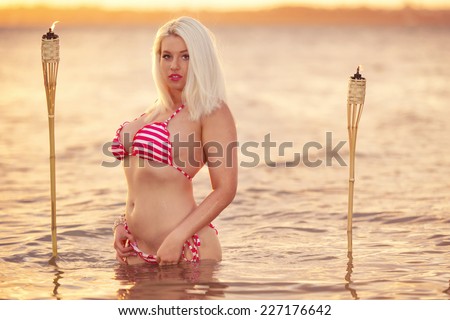 Beautiful blonde woman posing in a bikini on the beach at sunset in Brisbane, Queensland, Australia.