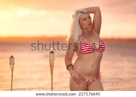 Beautiful blonde woman posing in a bikini on the beach at sunset in Brisbane, Queensland, Australia.