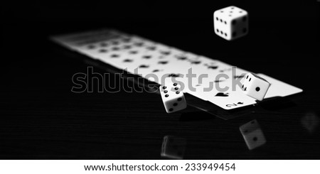 High contrast black and white image of gaming dice and a row of playing cards.