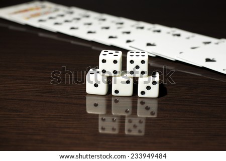 High contrast black and white image of gaming dice and a row of playing cards.