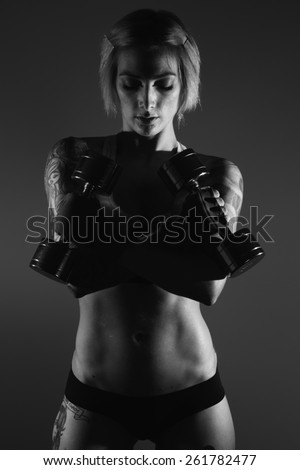 Black and white image of a young female fitness model posing in studio.