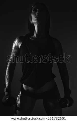 Black and white image of a young female fitness model posing in studio.