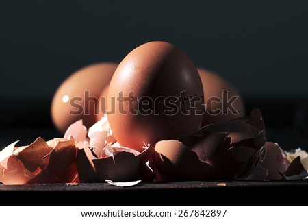 Low light with high contrast lighting of a bunch of eggs whole and crushed shells.
