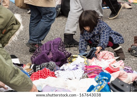 Harajuku, Japan - December 8: Unidentified kid choose the second hand clothes at flea market in Yoyogi Park, Harajuku on December 8, 2013.