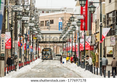 Yokohama, Japan - February 8, 2014: Japanese people walks across the street in snow storm in Yokohama, Japan