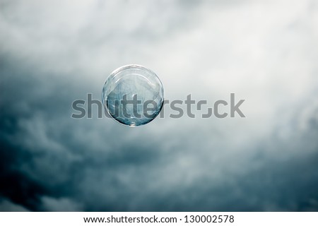 Single floating bubble in front of a dark mysterious sky