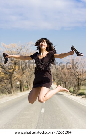 Happy girl jumping in the middle of the road