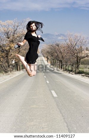Happy girl jumping in the middle of the road