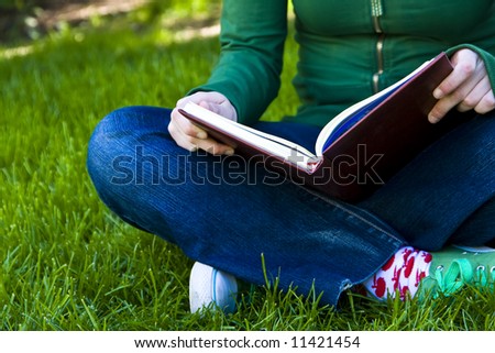 Young female student reading on the grass