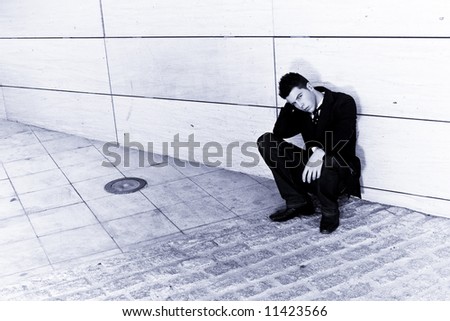 Depressed businessman in urban background, blue toned.