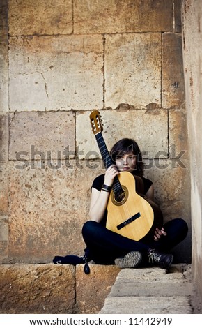 Young guitar performer against brickwall