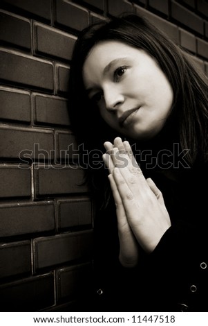 Praying woman in dark sepia tone.
