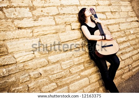 Street artist holding guitar on the wall
