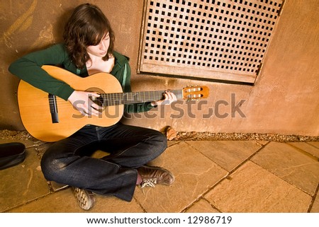 Young guitar performer in urban background.