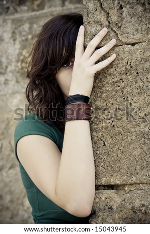 Hidden young woman behind stone wall
