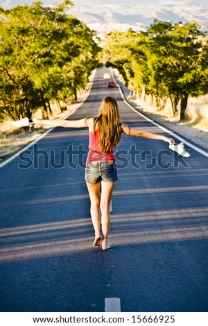 Young barefoot woman balancing in the middle of the road
