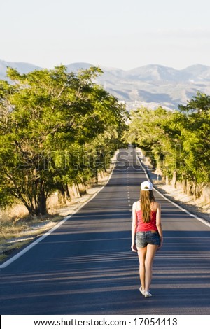 Young woman walking in the middle of the road.